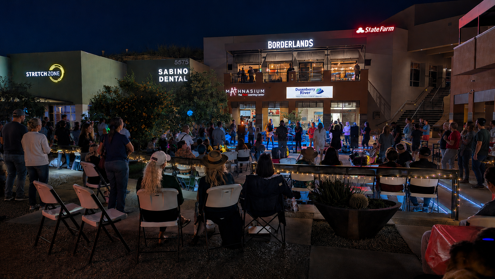 A shopping center plaza glowing and busy at dusk