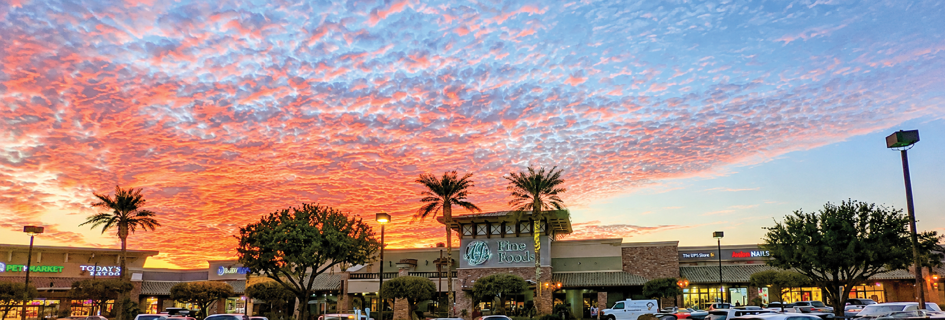 A shopping center glowing beneath a dramatic desert sunset